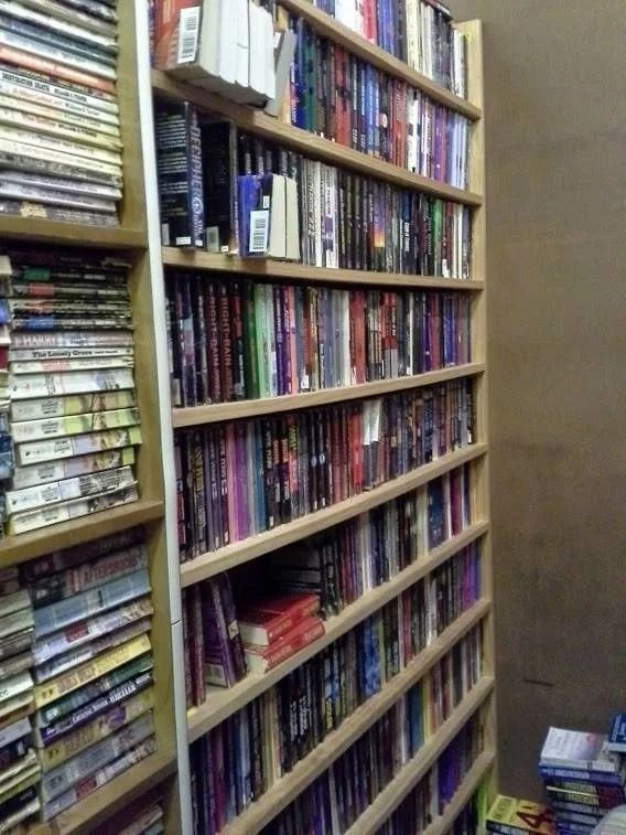 Rows of colorful books on tall shelves in a narrow bookstore aisle