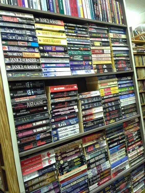 Bookshelves overflowing with books in a bookstore. Many colorful spines fill the shelves.