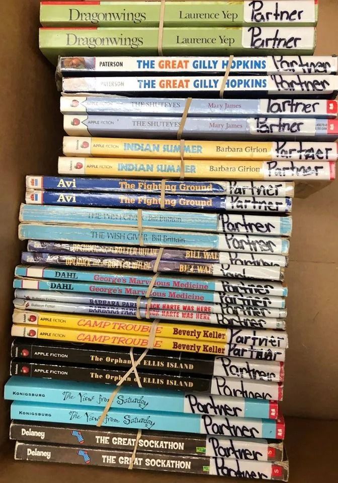 A stack of children's books tied with twine, inside a cardboard box. Titles are visible.
