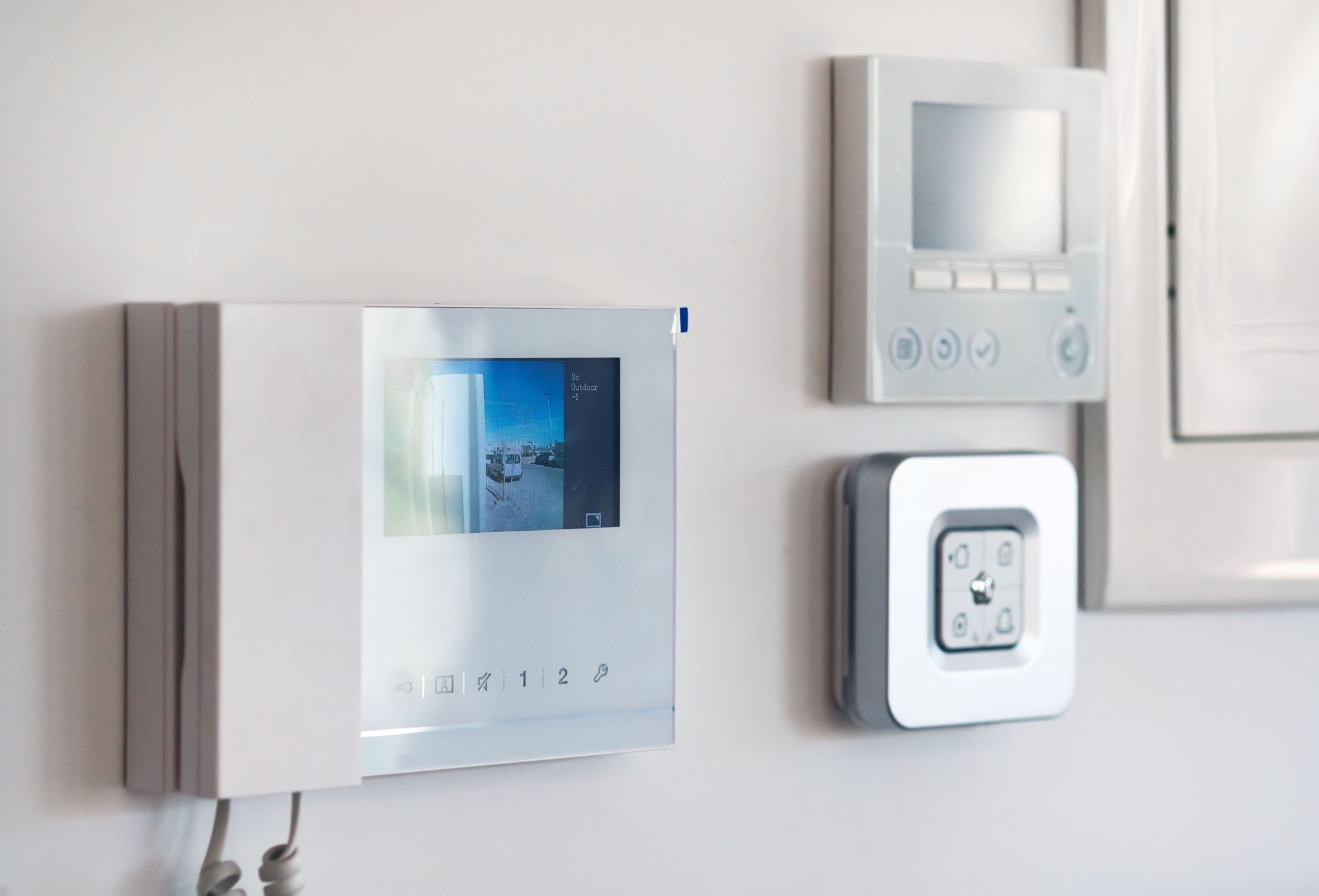 White wall with intercom, thermostat, and light switch.