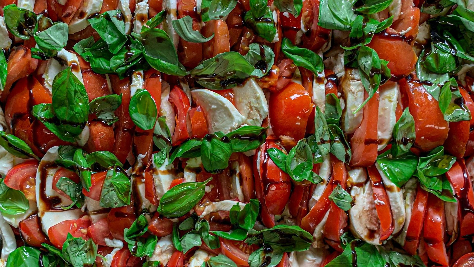 A close up of a salad with tomatoes , basil and mozzarella.