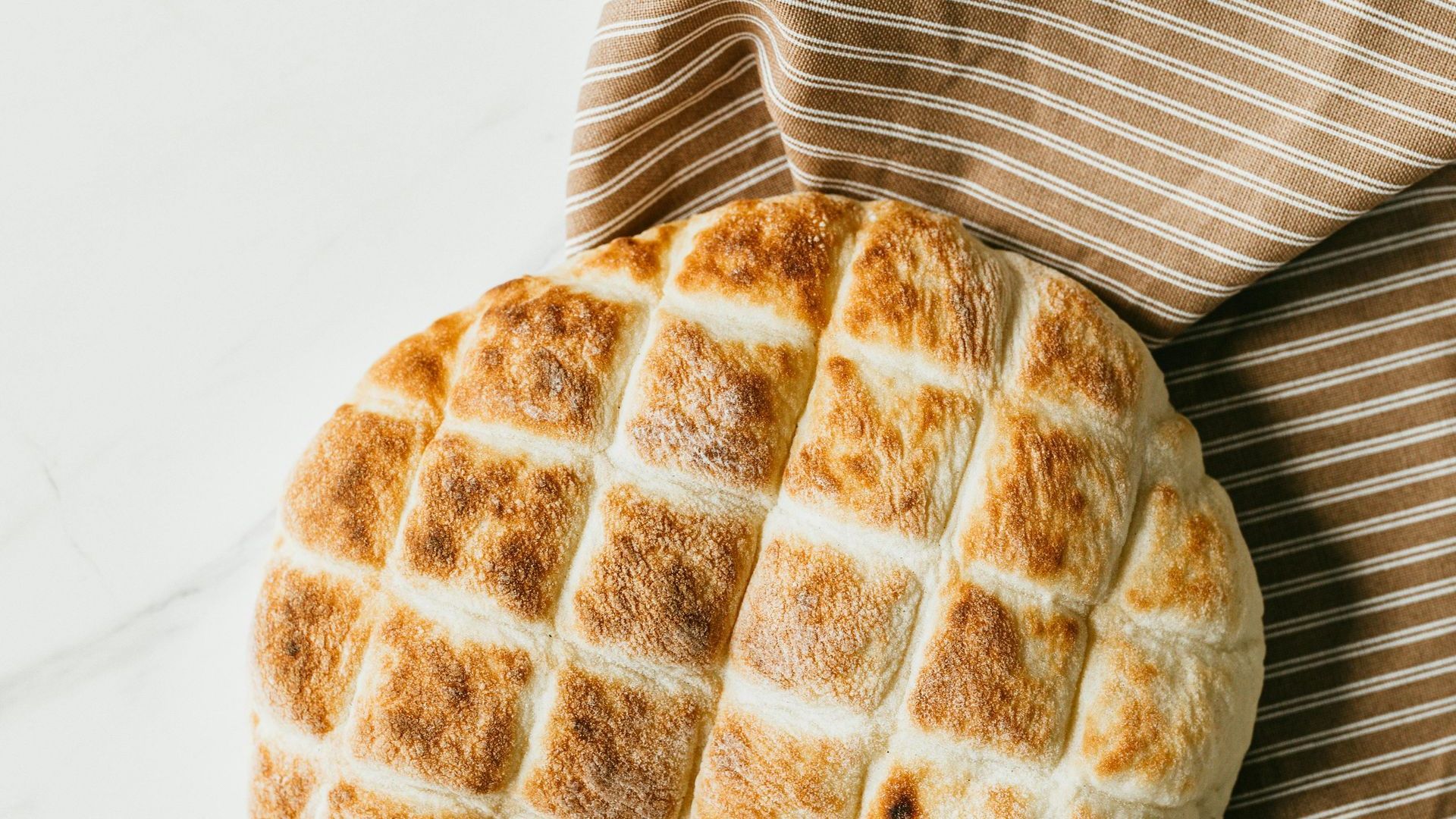 A loaf of bread is sitting on a towel on a table.