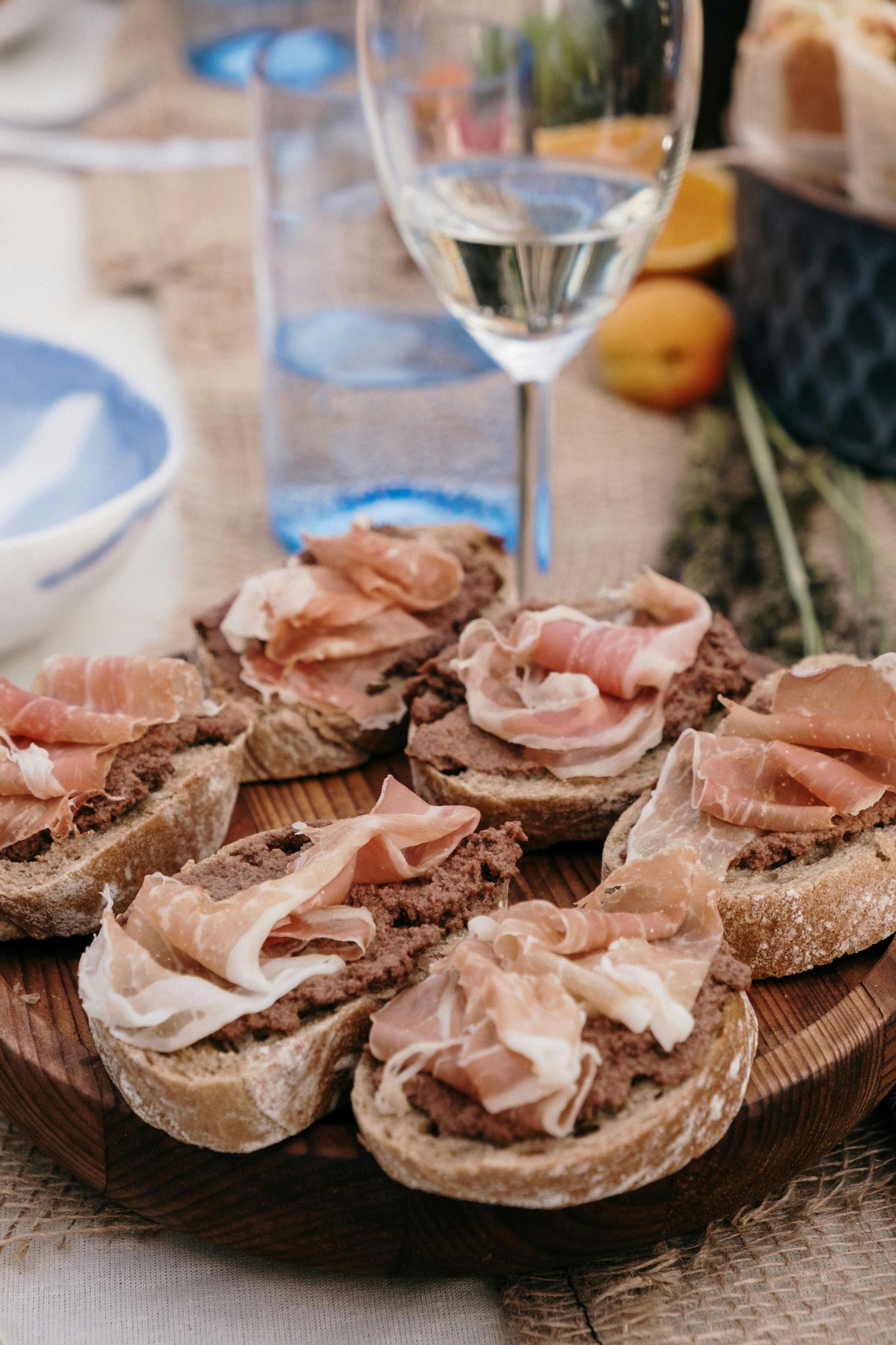 A wooden cutting board topped with sandwiches and a glass of wine.