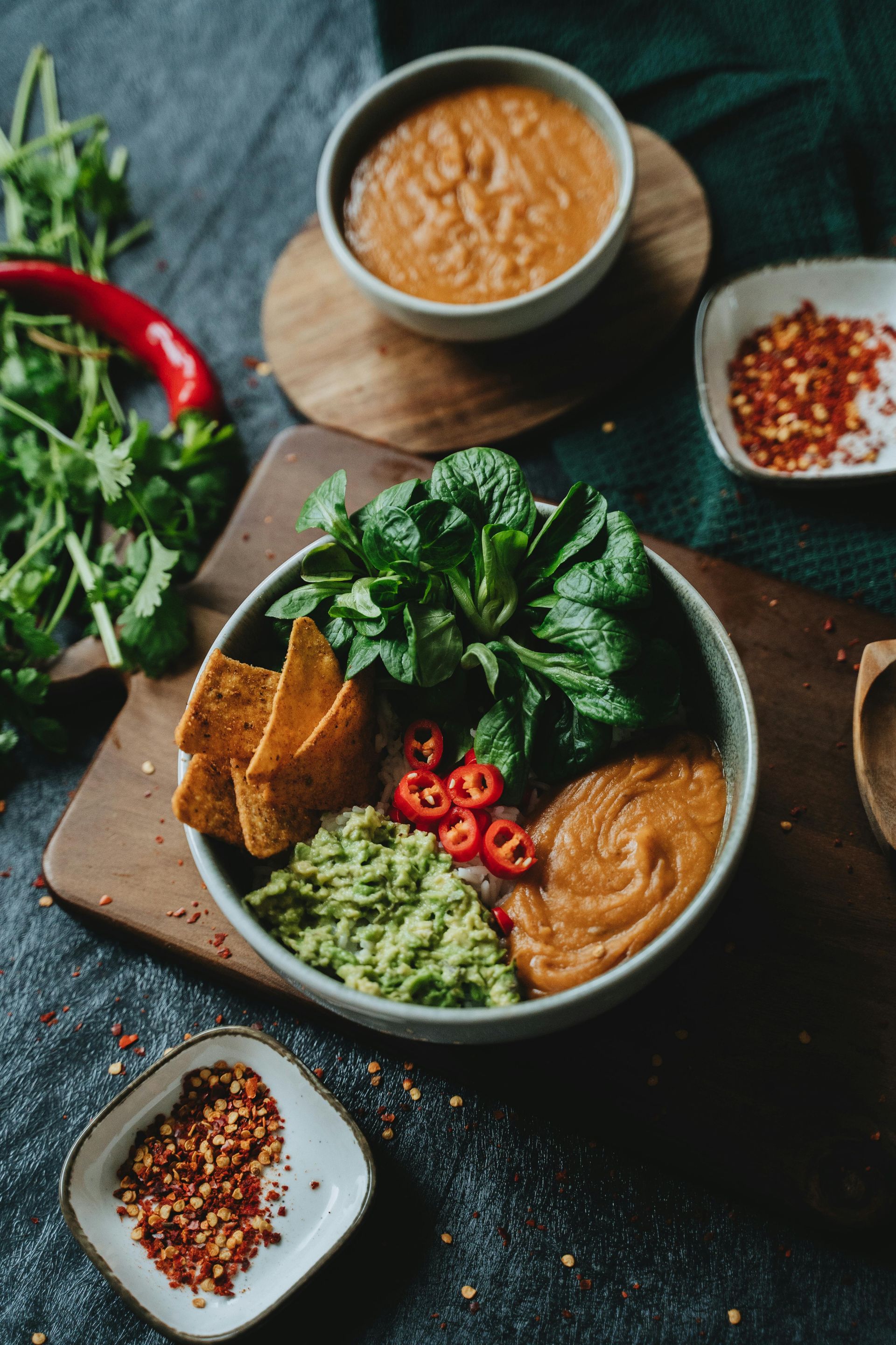 A bowl of guacamole , tortilla chips , and soup on a table.