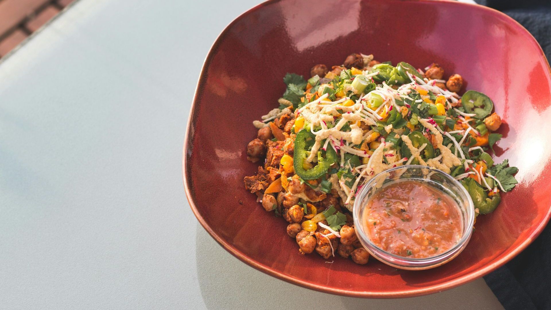 A bowl of food with a dipping sauce on a table.