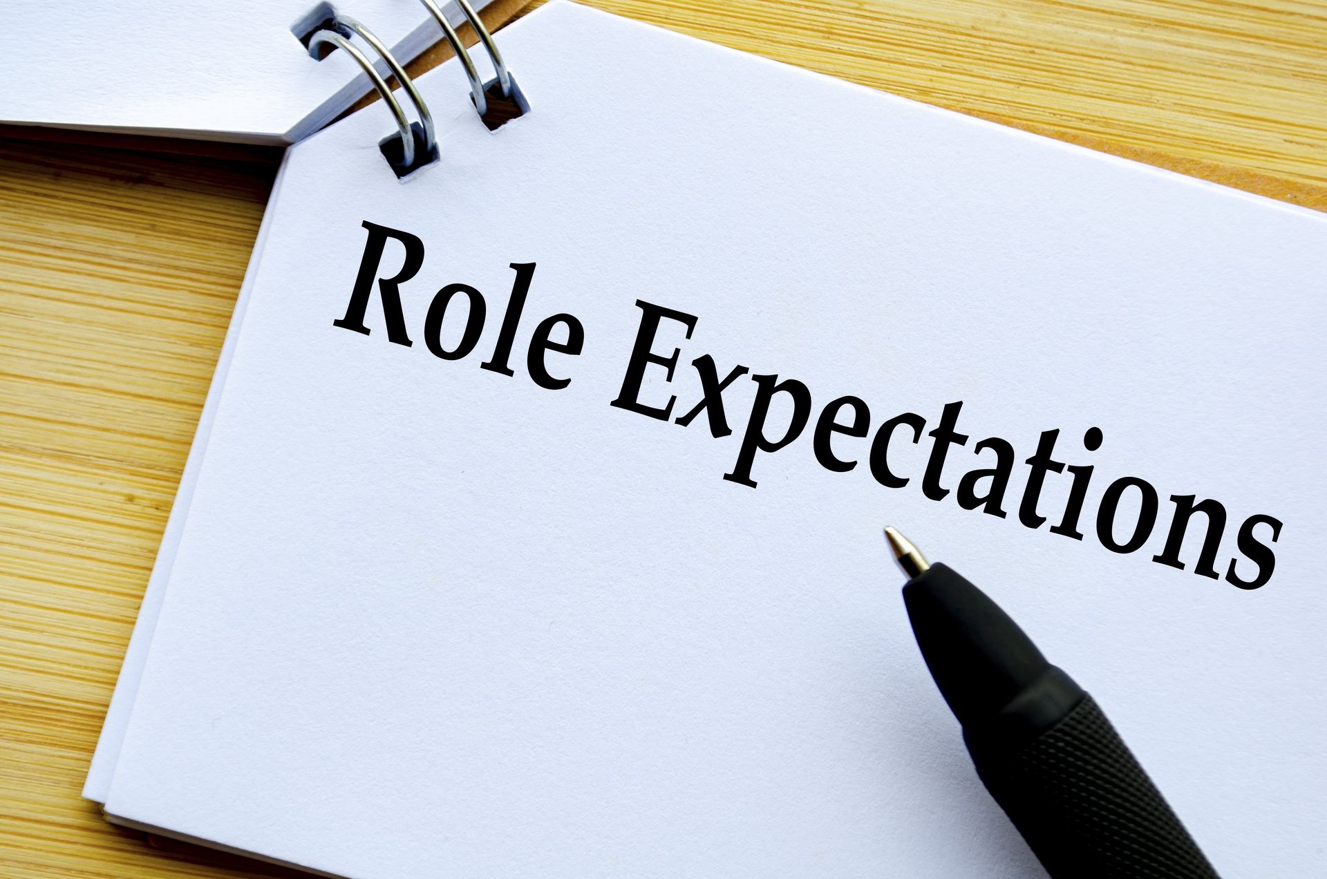 Notebook page reading “Role Expectations” with a pen on a wooden desk