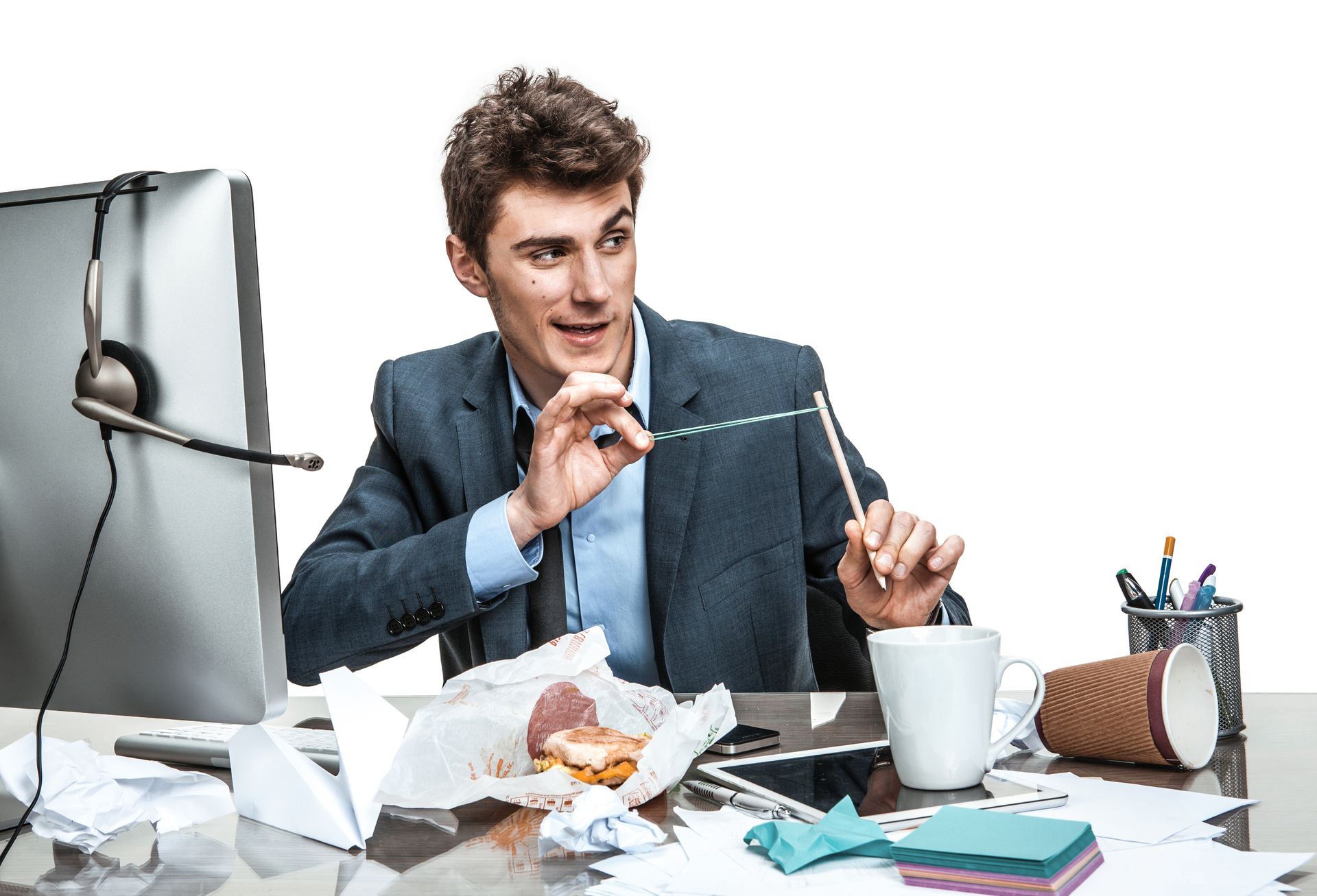 Man at desk with coffee and snacks, balancing a pen between two wire fixtures while looking focused