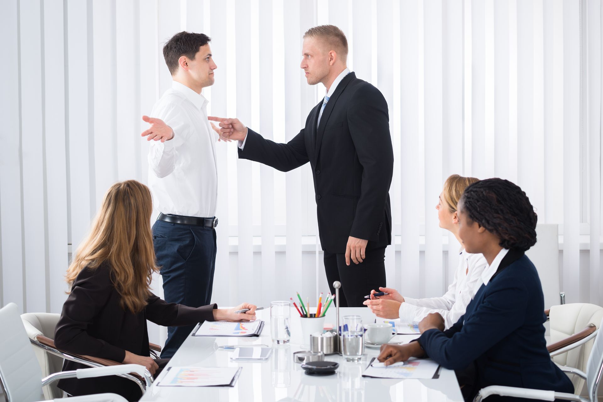 A business meeting with one man point his finger in an aggressive manner towards a colleague