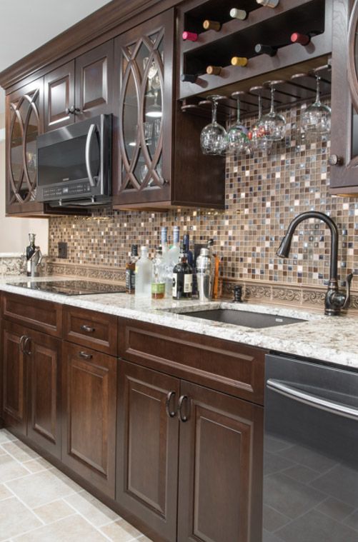 A kitchen with wooden cabinets , granite counter tops , a sink , a microwave , and a wine rack.