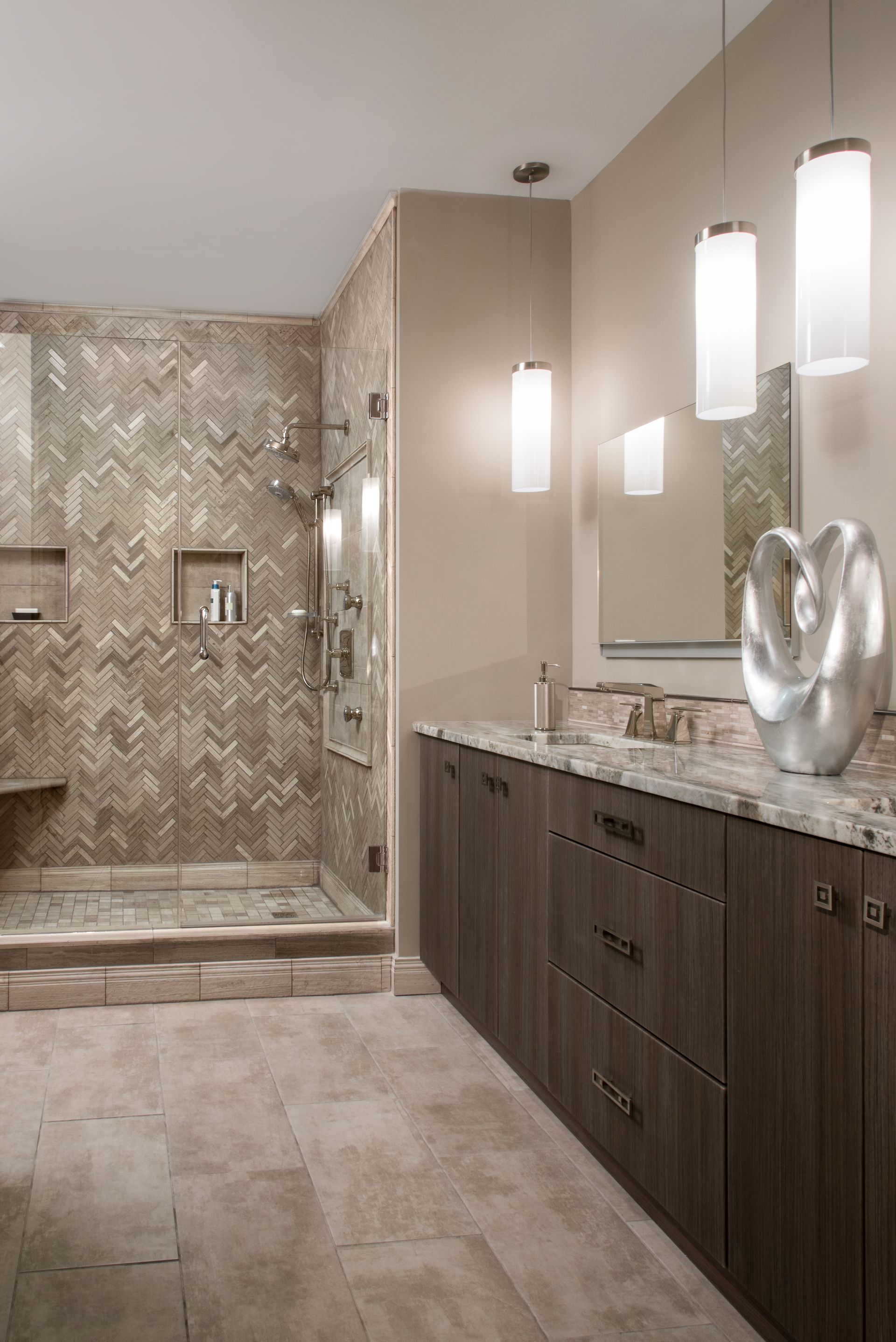 Modern beige bathroom with walk-in shower, dark wood vanity, and hanging pendant lights