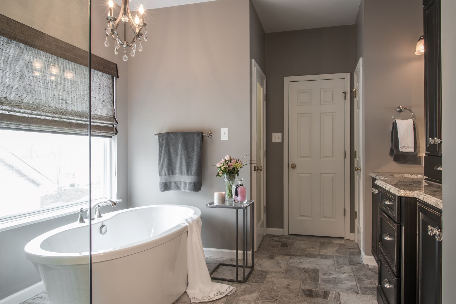Luxury bathroom with a freestanding tub, double vanity, tiled floor, and window with blinds