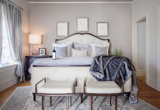 Bright bedroom with a white bed, gray accents, and two benches at the foot of the bed.