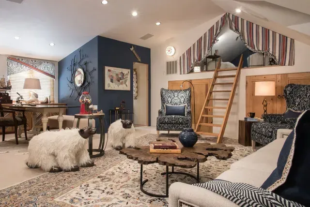 A living room with a couch , chairs , a table and a staircase.