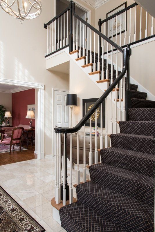 A staircase with a black carpet and a white railing