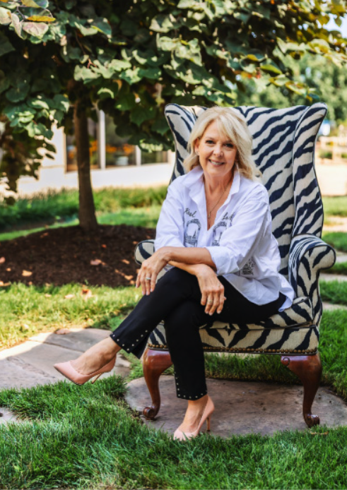 A woman is sitting in a zebra print chair in the grass.