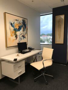 An office with a desk and chair and a painting on the wall