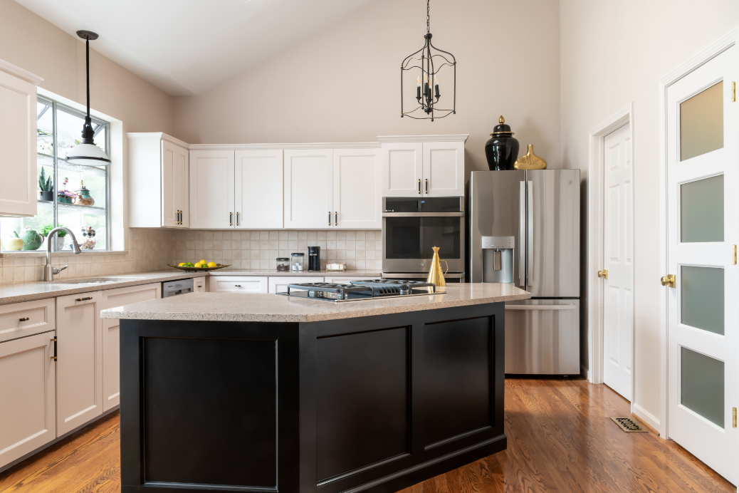 A kitchen with white cabinets , stainless steel appliances , and a black island.