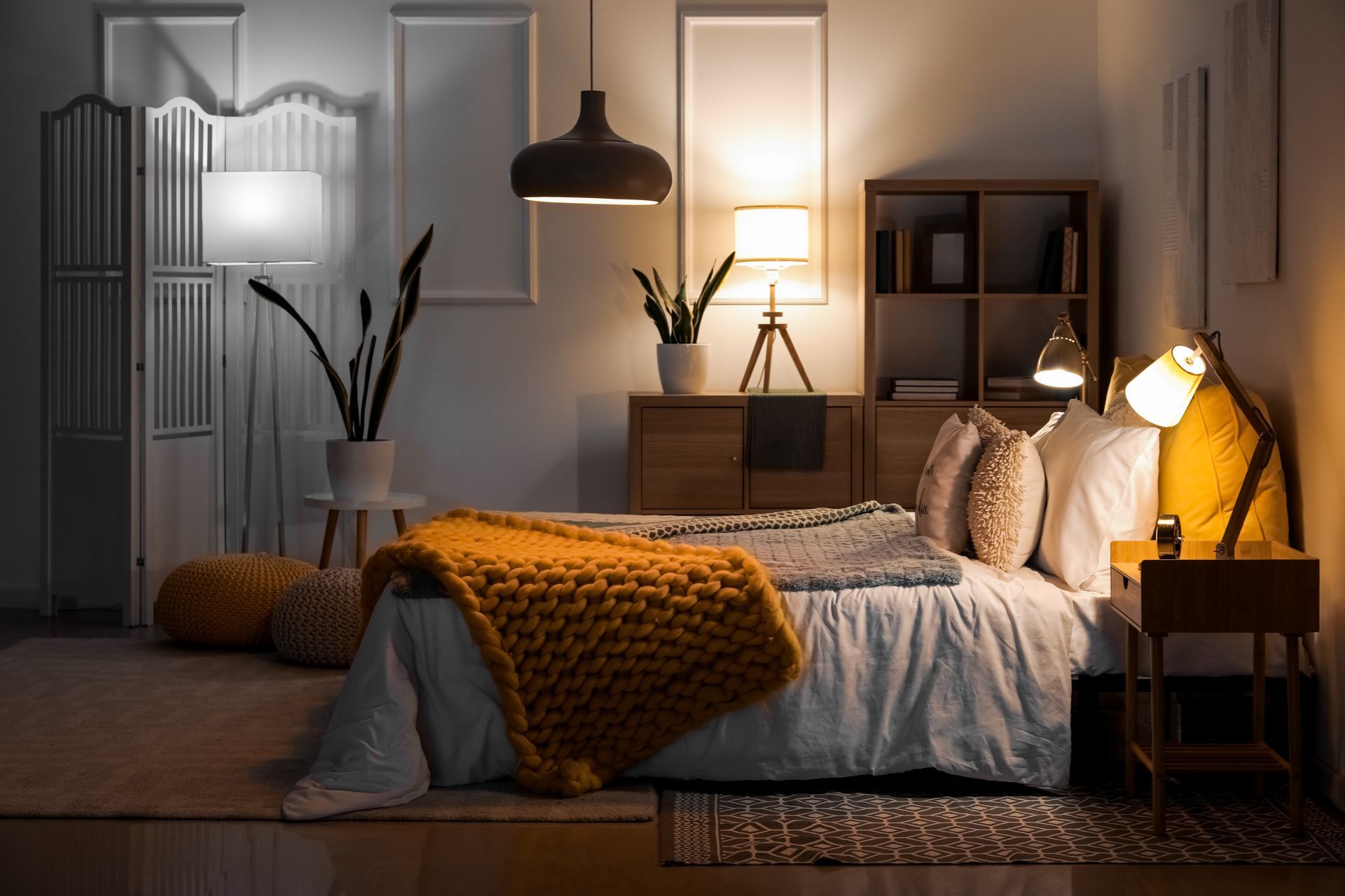 Cozy bedroom with bed, warm lamp light, orange throw, and dark modern decor