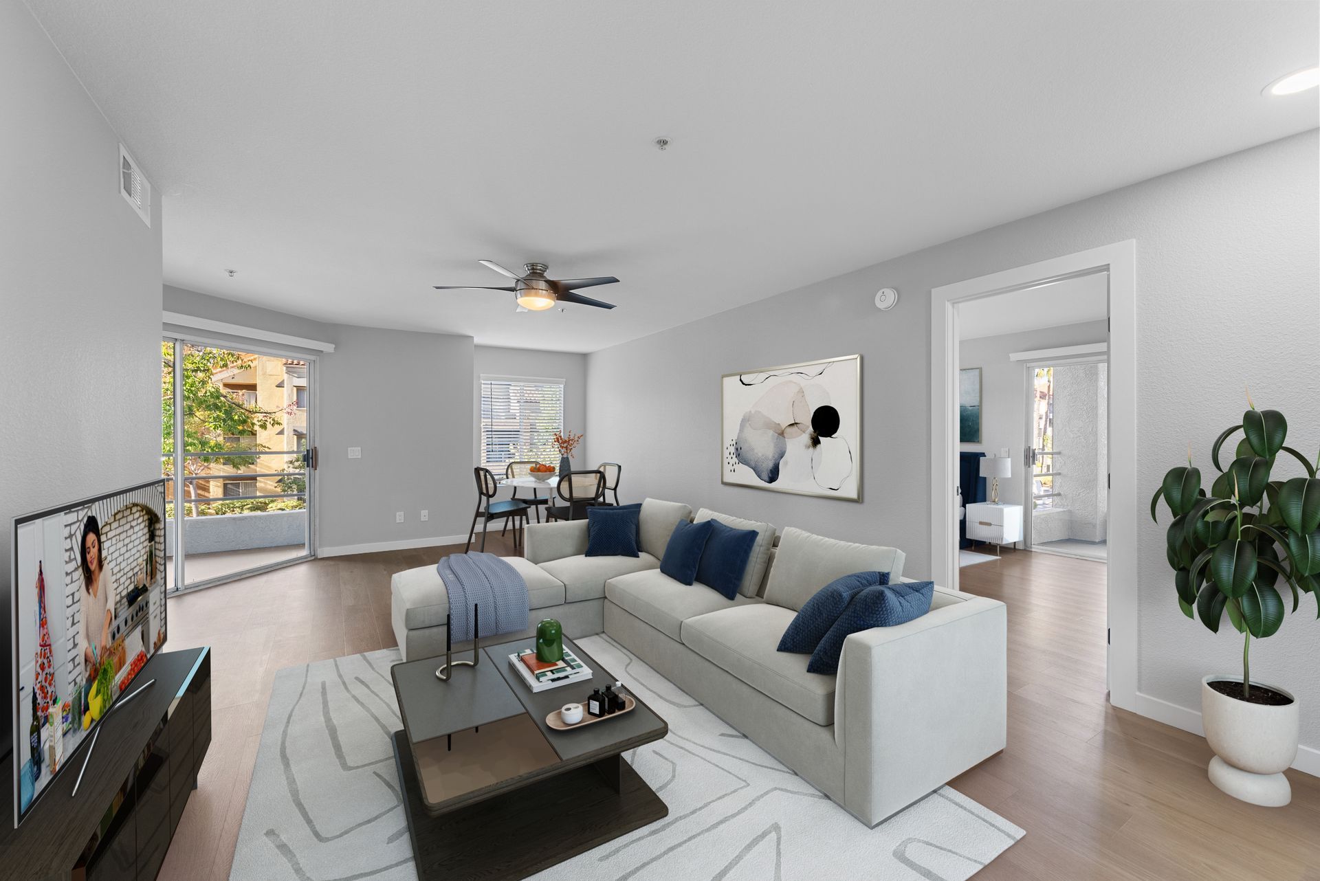 Living room with white sectional sofa, coffee table, and large window overlooking a balcony.