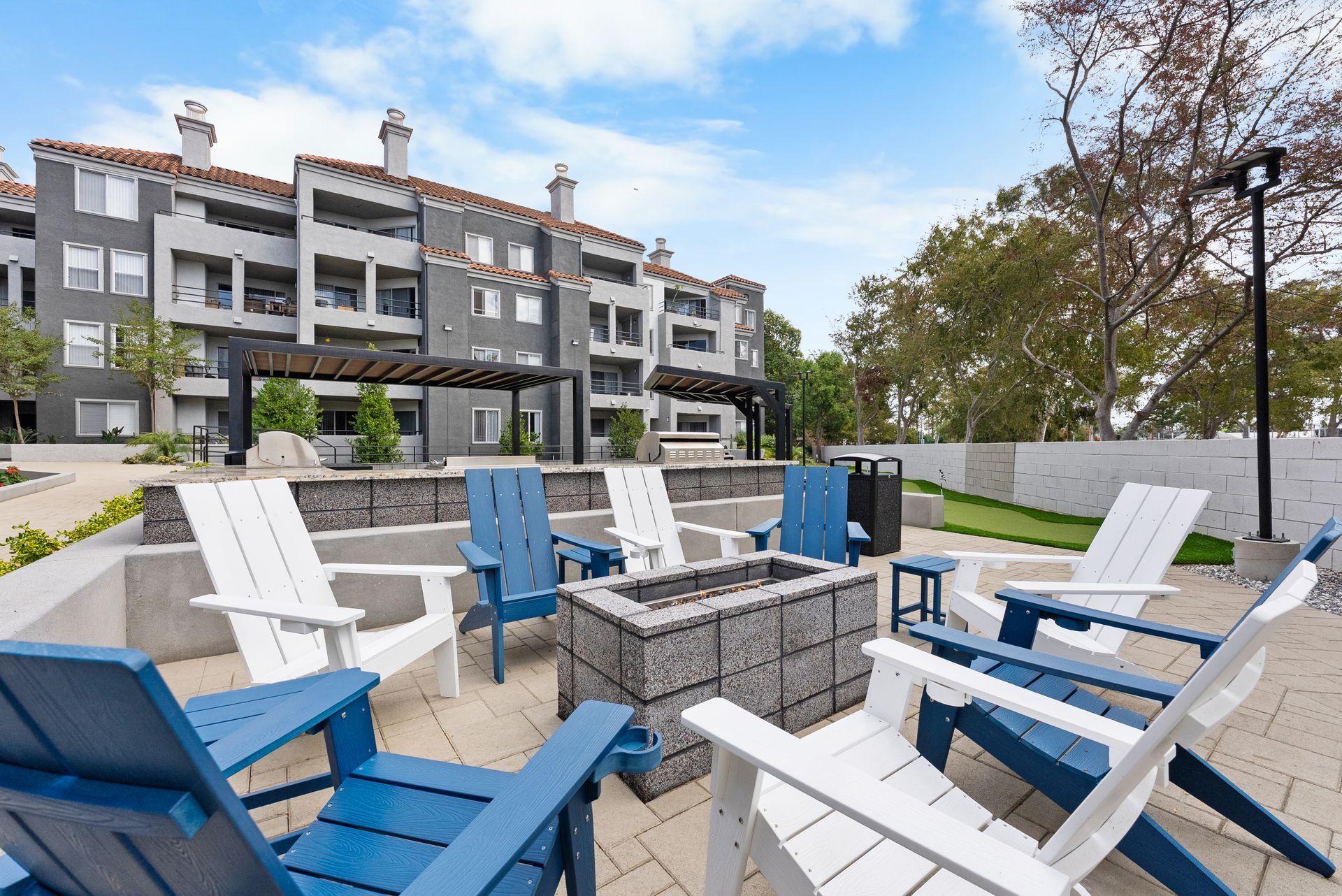 The Grand Costa Mesa fire pit area with blue and white Adirondack chairs around a fire pit 