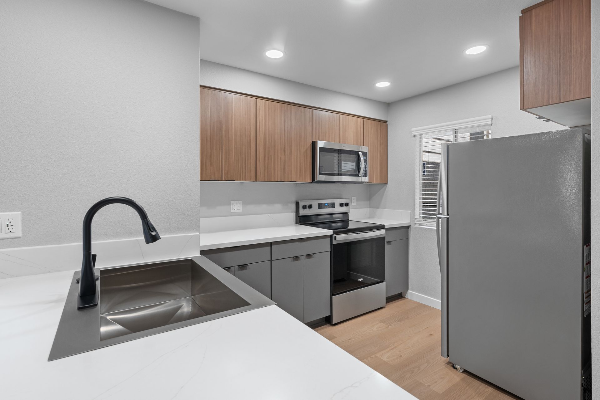 A kitchen with a sink, stove, refrigerator, and microwave.