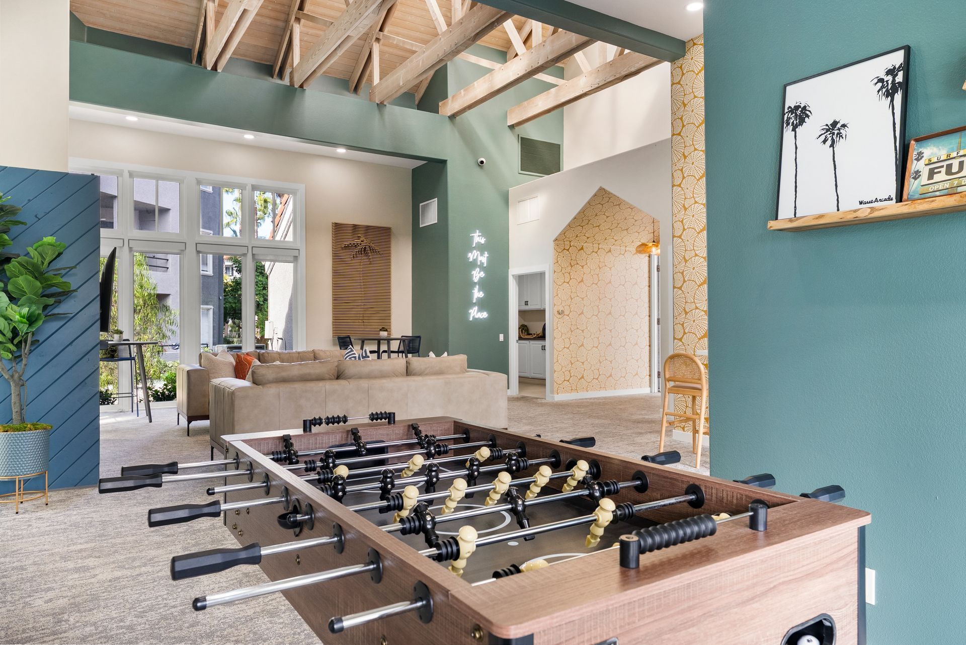 Foosball table in a modern rec room with couches, artwork, and a high ceiling.