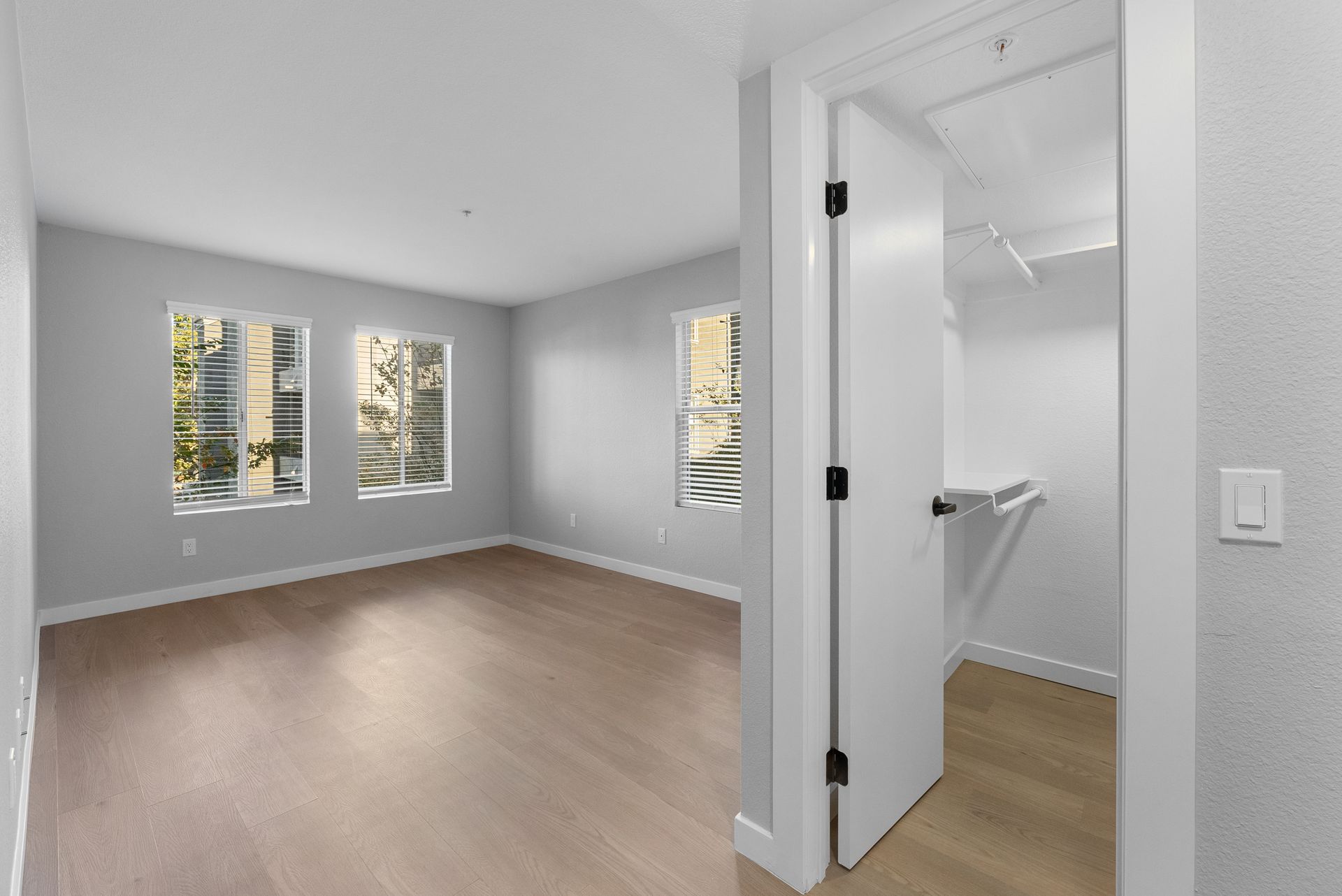 An empty bedroom with hardwood floors and a walk in closet.