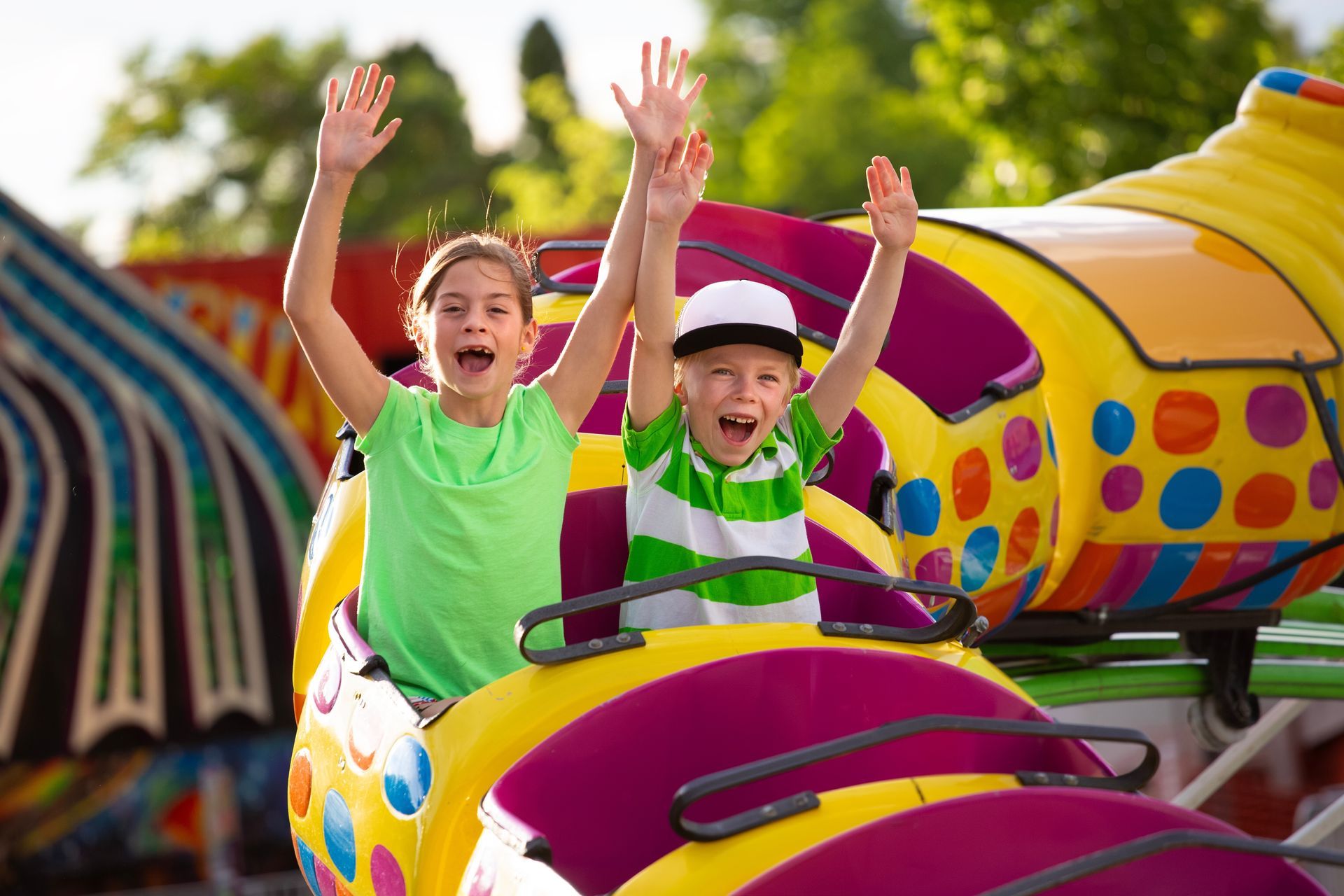 A boy and a girl are riding a roller coaster at a carnival.