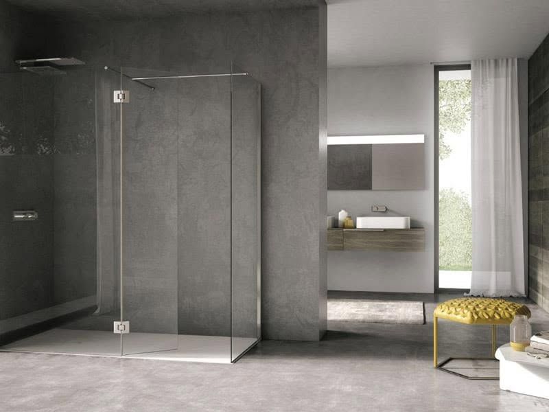 Bagno minimalista sui toni del grigio con box doccia in vetro, ripiano per il lavabo, finestra e sgabello giallo.