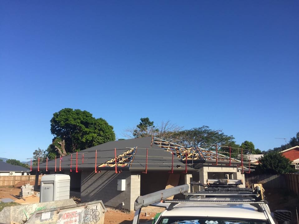 House under construction with roof framing, gray walls, and clear blue sky.— Roof 4 U in Alice River, QLD