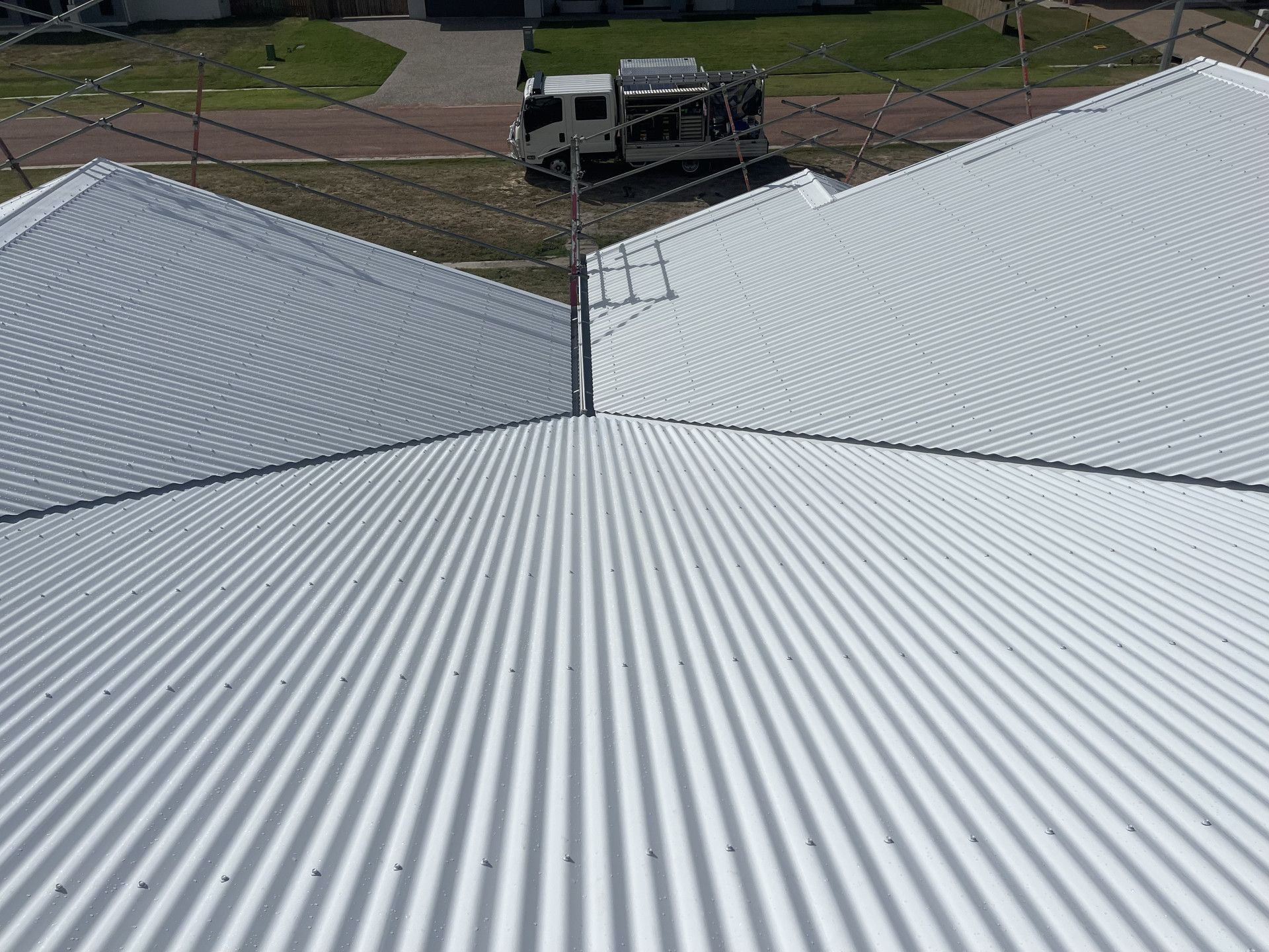 White corrugated metal roof with utility vehicle in the background.— Roof 4 U in Alice River, QLD