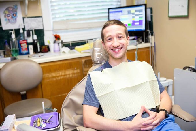 A man is smiling while sitting in a dental chair.