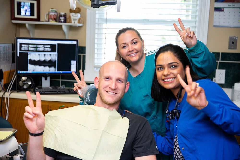 A man in a dental chair giving a peace sign