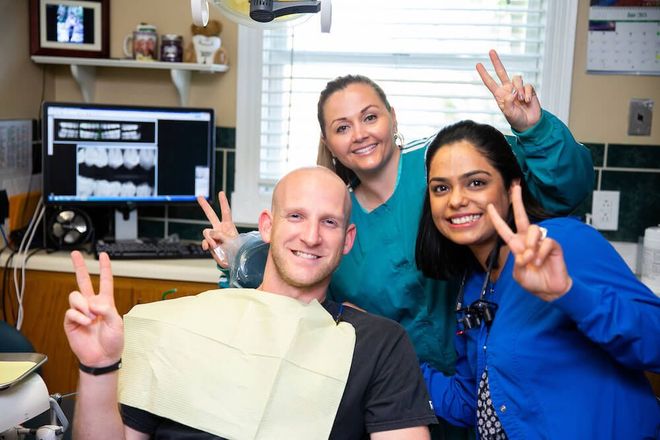 A man in a dental chair giving a peace sign