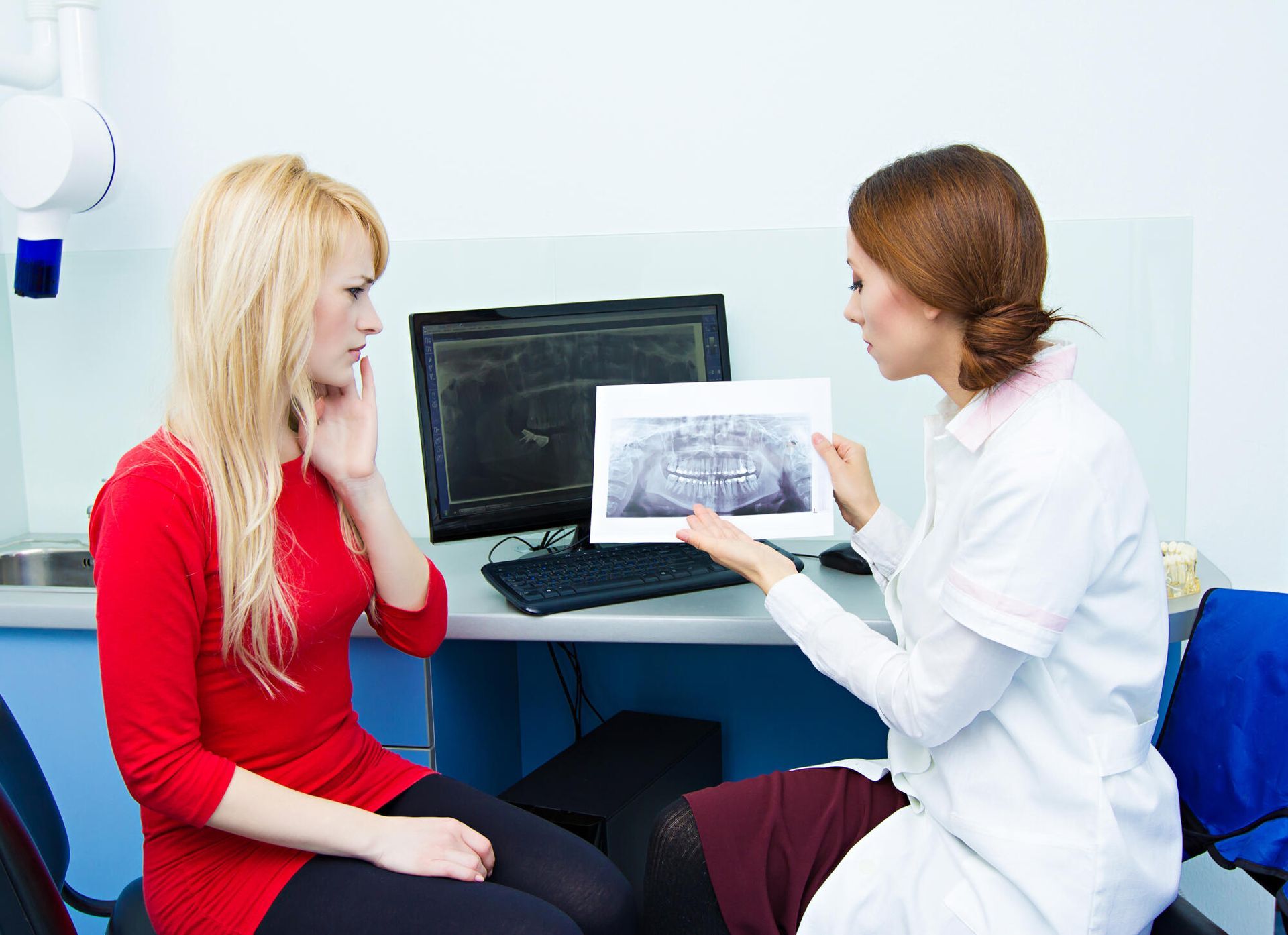 Doctor showing an X-ray to a seated patient in a clinic room