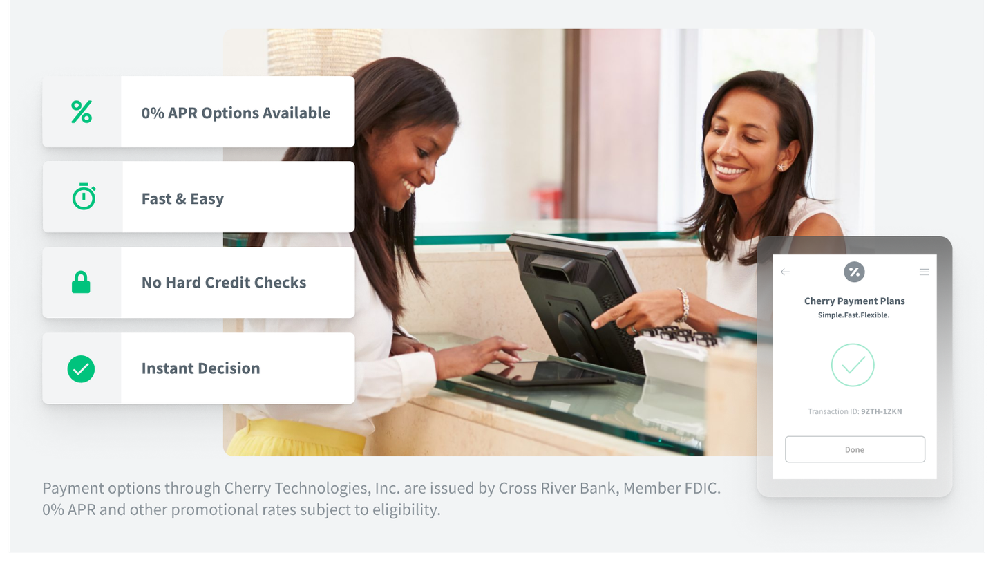 Two women are sitting at a counter using a computer.