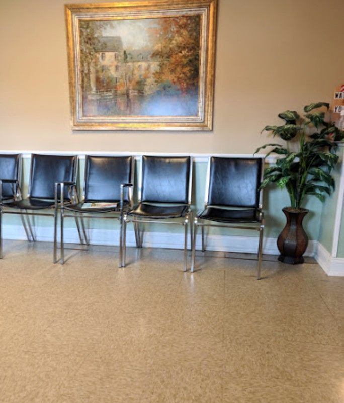 A row of chairs in a waiting room with a picture on the wall above them
