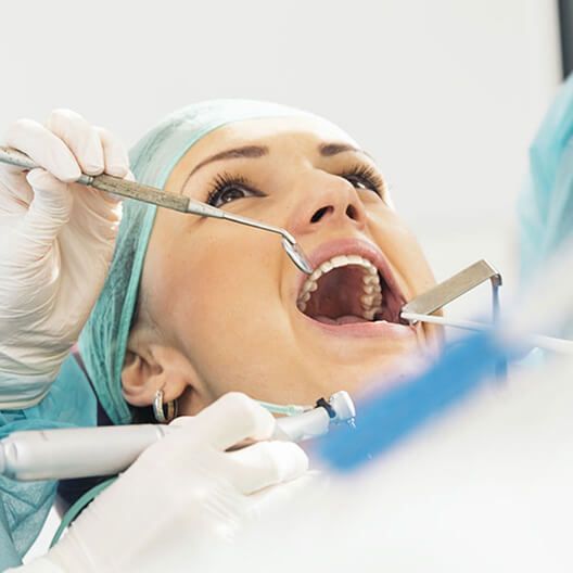 A woman is getting her teeth examined by a dentist