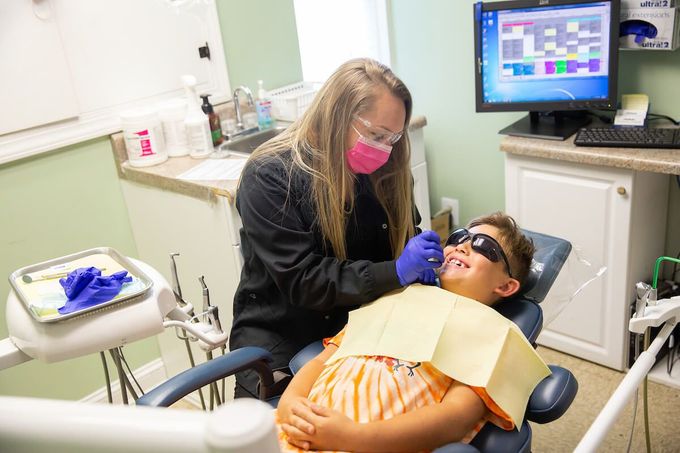 A dentist is examining a young boy 's teeth in a dental office.