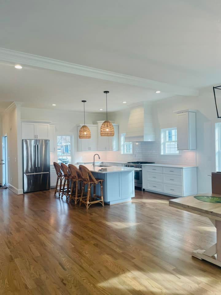 a kitchen with hardwood floors , white cabinets , stainless steel appliances and a large island .