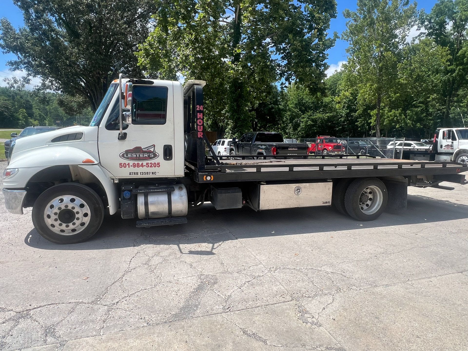 Red tow truck parked on gravel with trees in the background