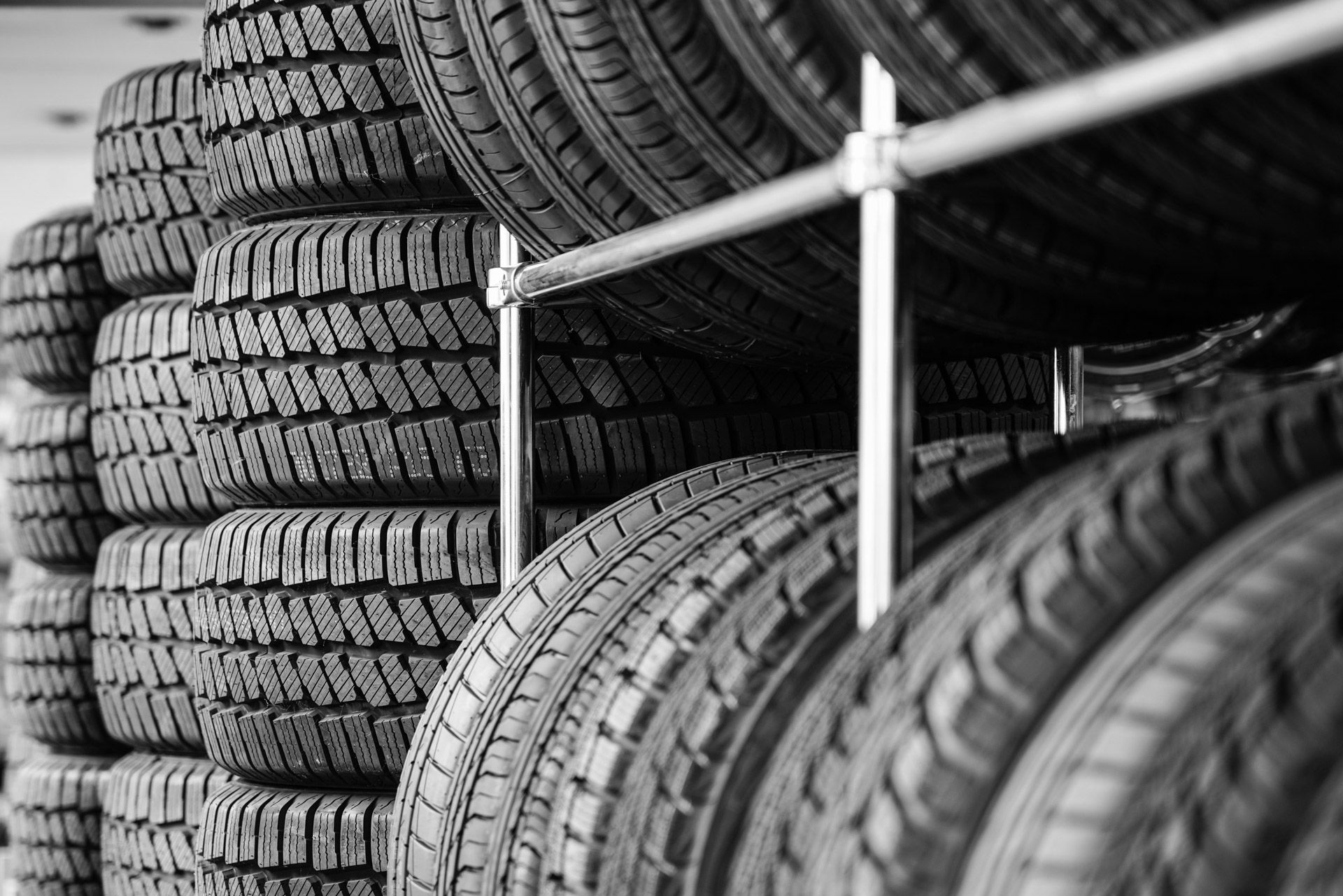 Stacks of black tires in a warehouse, with a metal rack in the foreground.