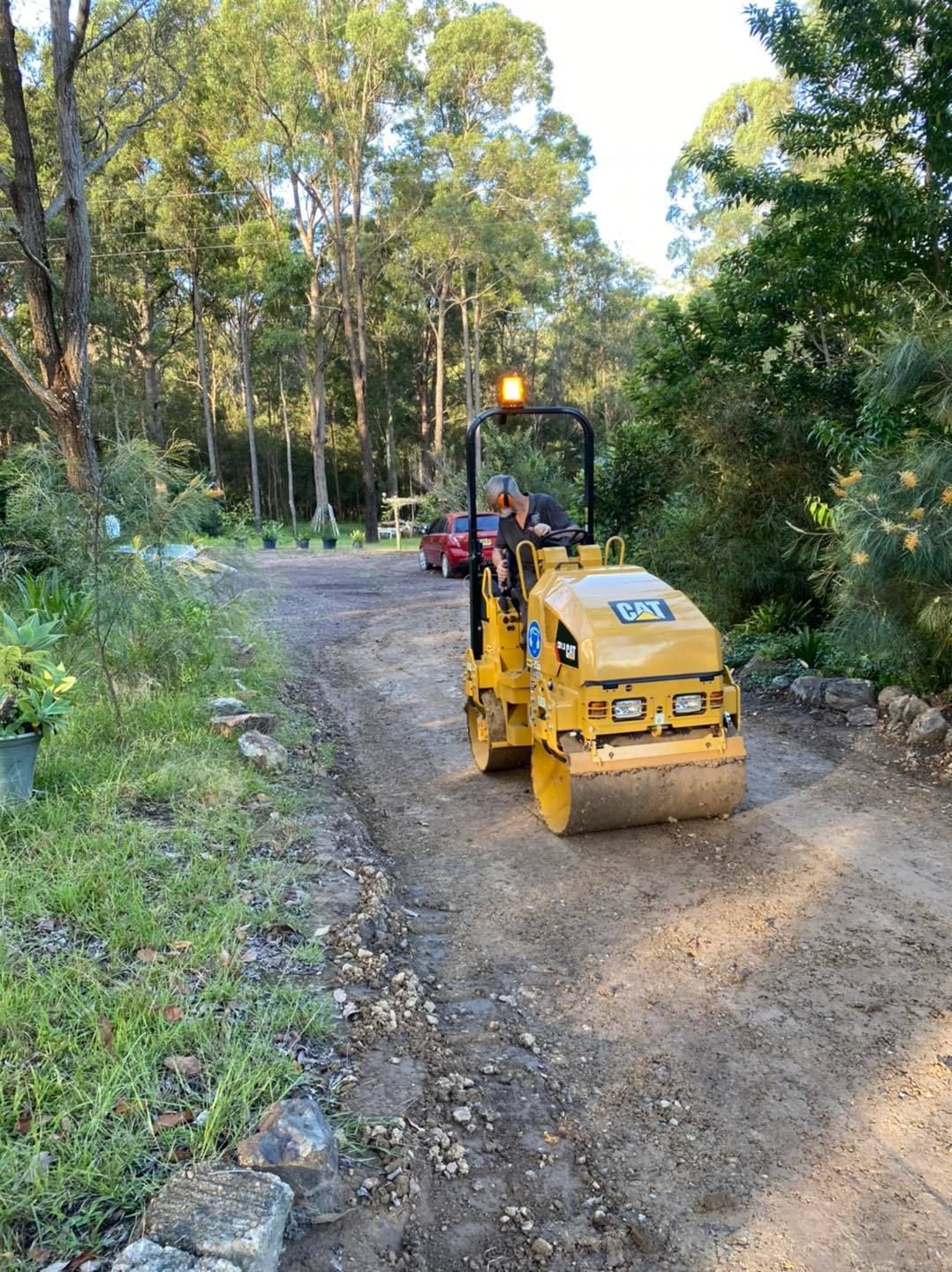 Yellow Road Roller Compacting Gravel Driveway With Trees in the Background — Ovannah Hire In West Kempsey, NSW