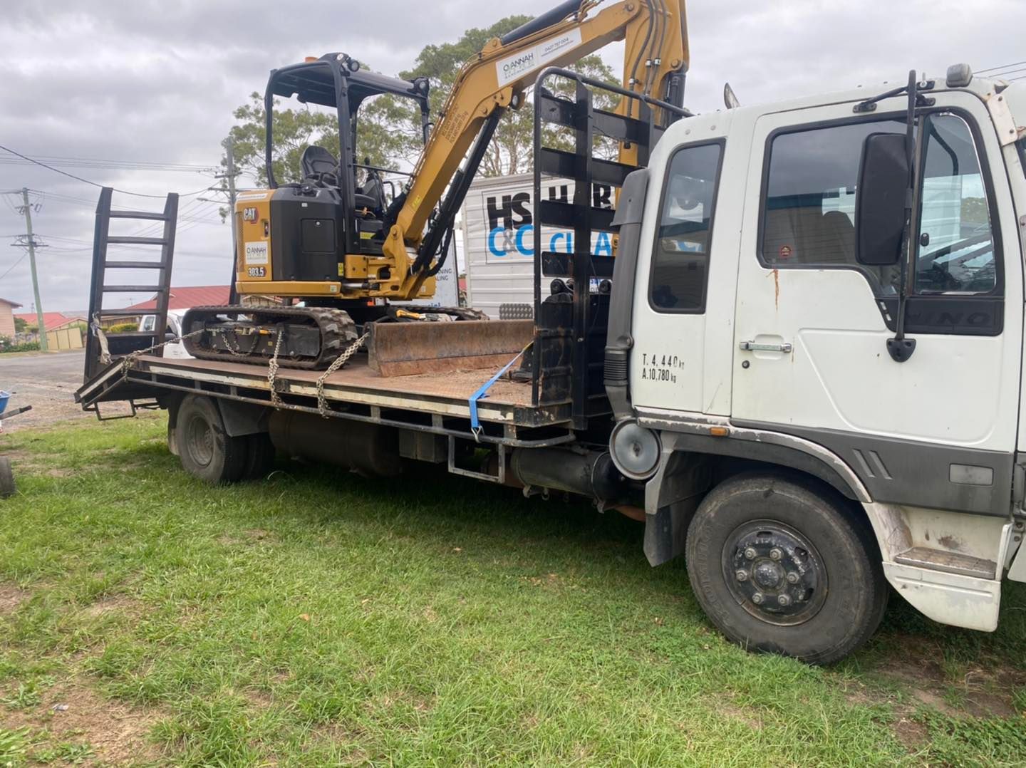 Yellow Excavator on a Flatbed Truck on Grass — Ovannah Hire In West Kempsey, NSW