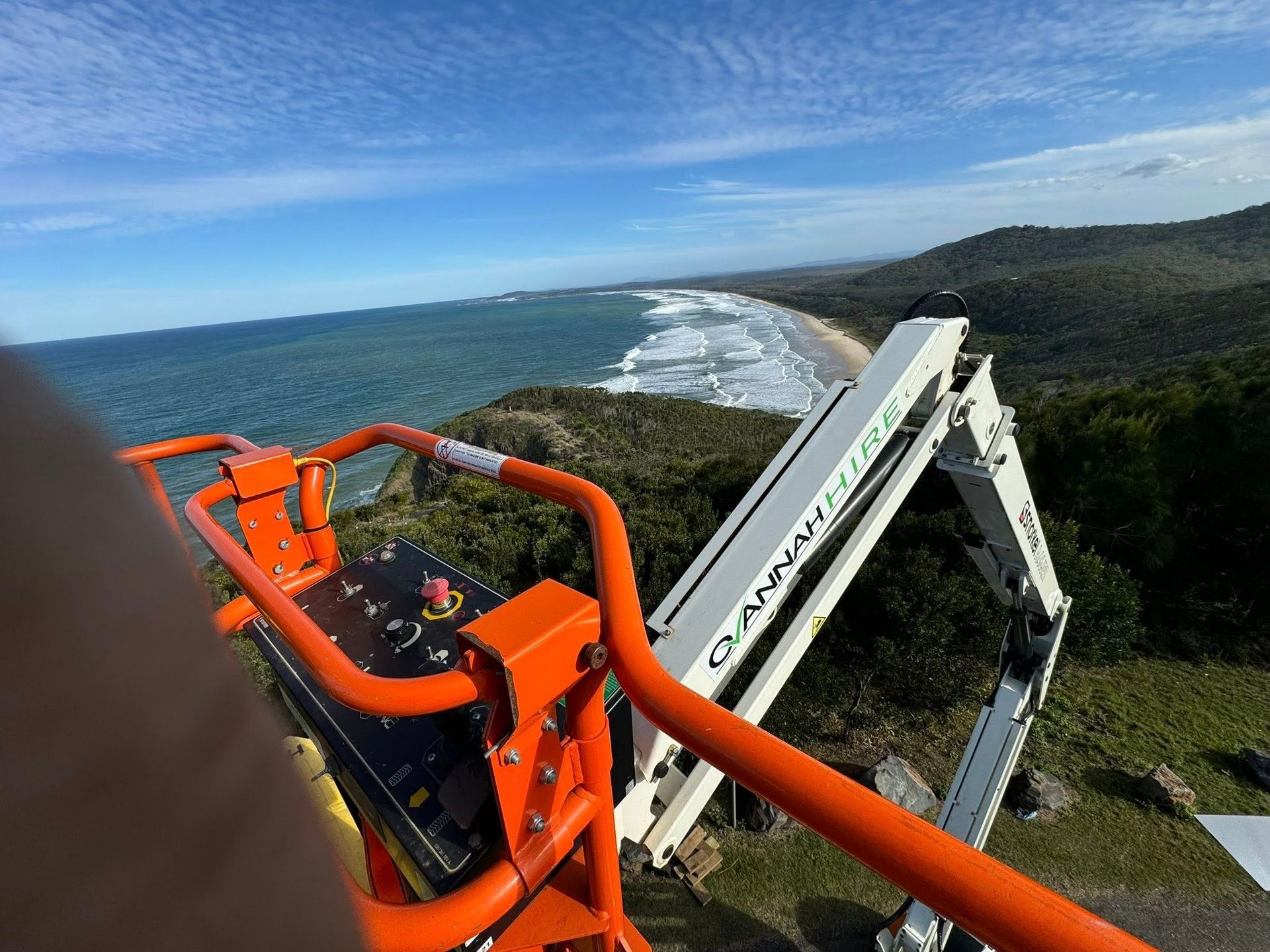 Orange Boom Lift Overlooking a Beach and Ocean on a Sunny Day — Ovannah Hire In West Kempsey, NSW