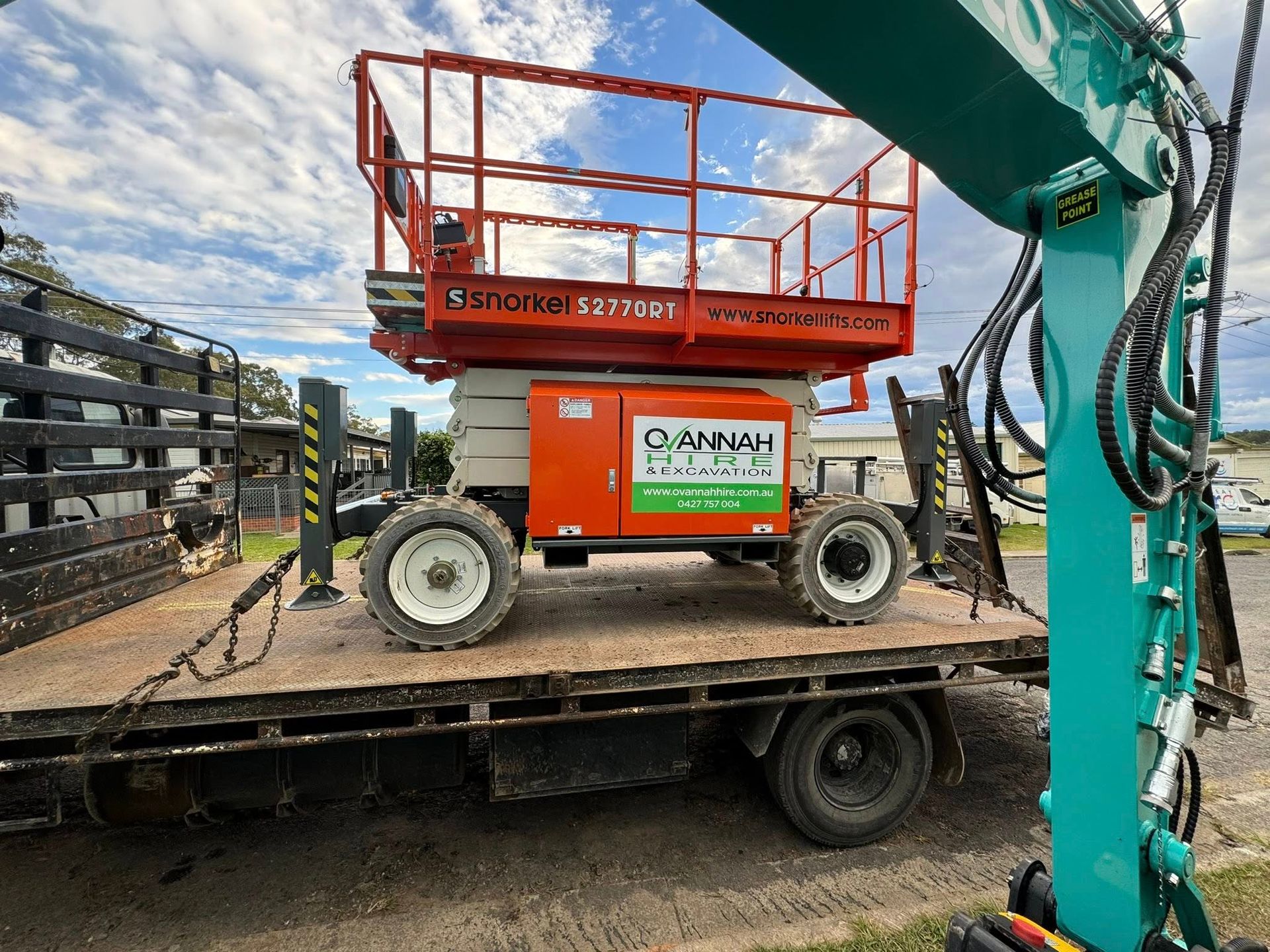 Orange Lift on a Flatbed Truck, Being Loaded by a Green Excavator — Ovannah Hire In West Kempsey, NSW