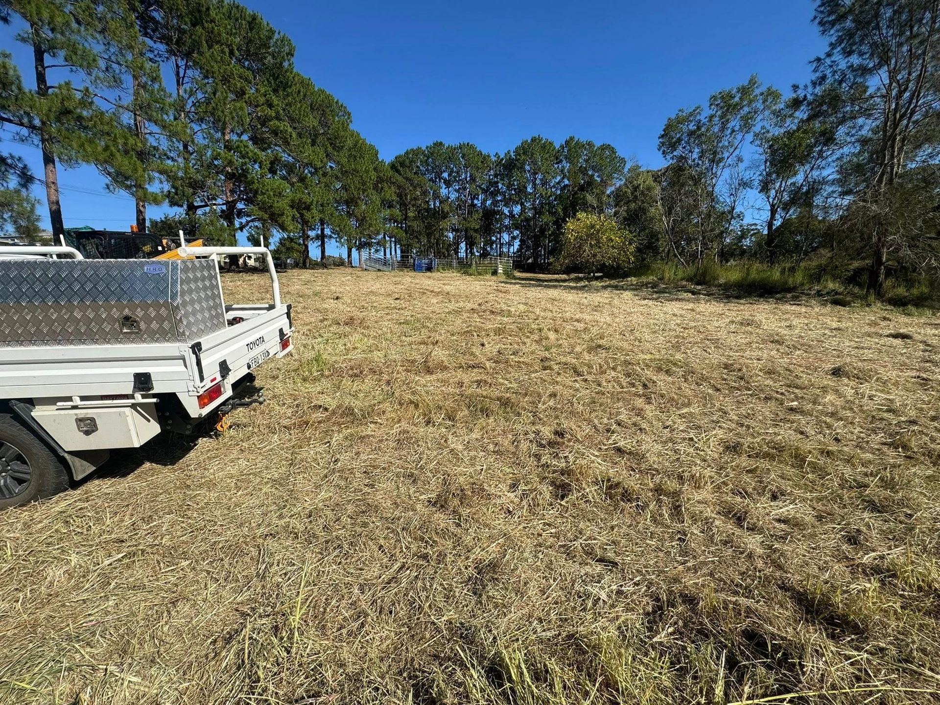 White Utility Truck Parked in a Grassy Field With Trees Under a Blue Sky — Ovannah Hire In West Kempsey, NSW