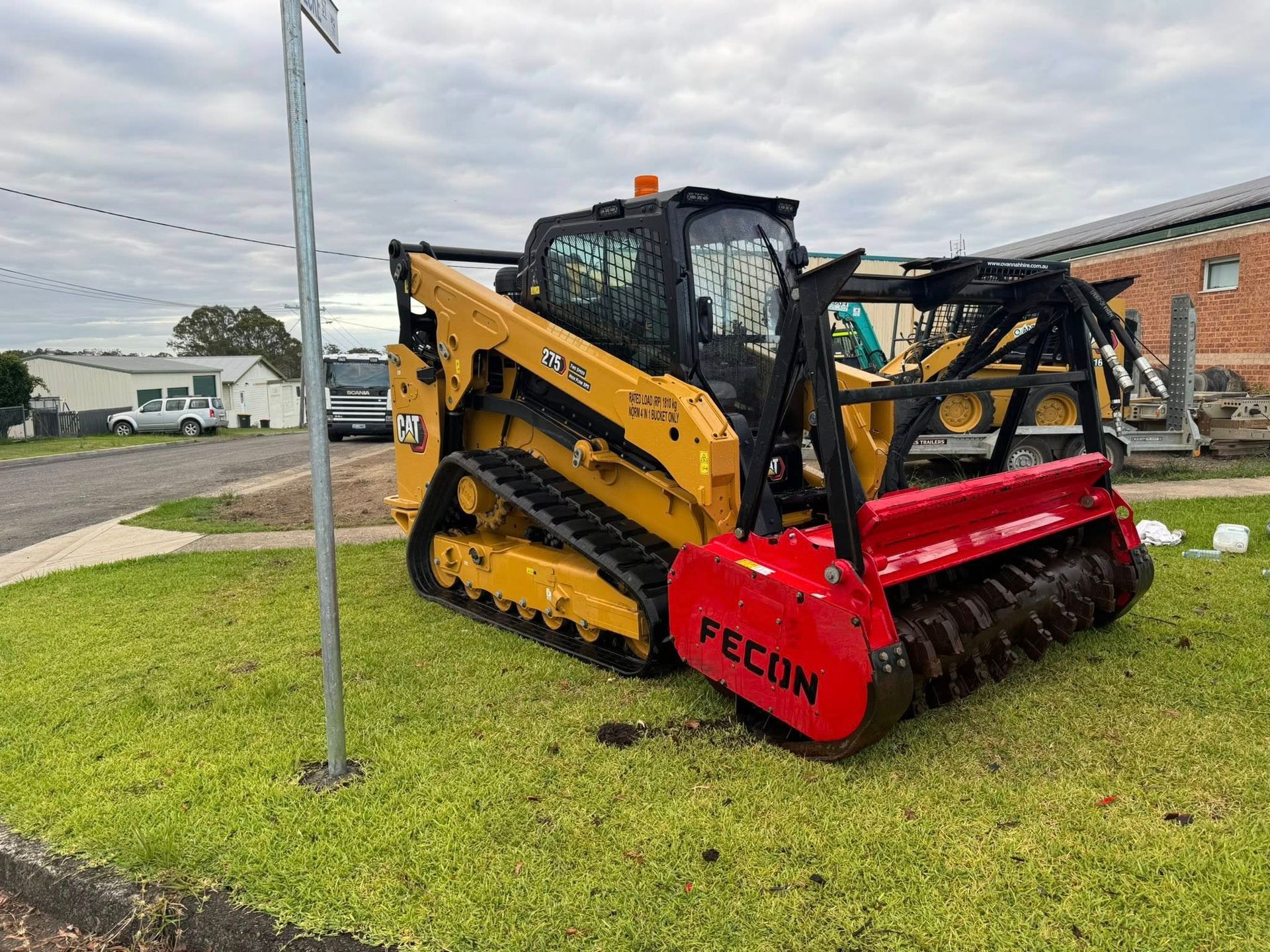 Yellow CAT Skid Steer With a Red Fecon Mulcher Attachment on Grass — Ovannah Hire In West Kempsey, NSW