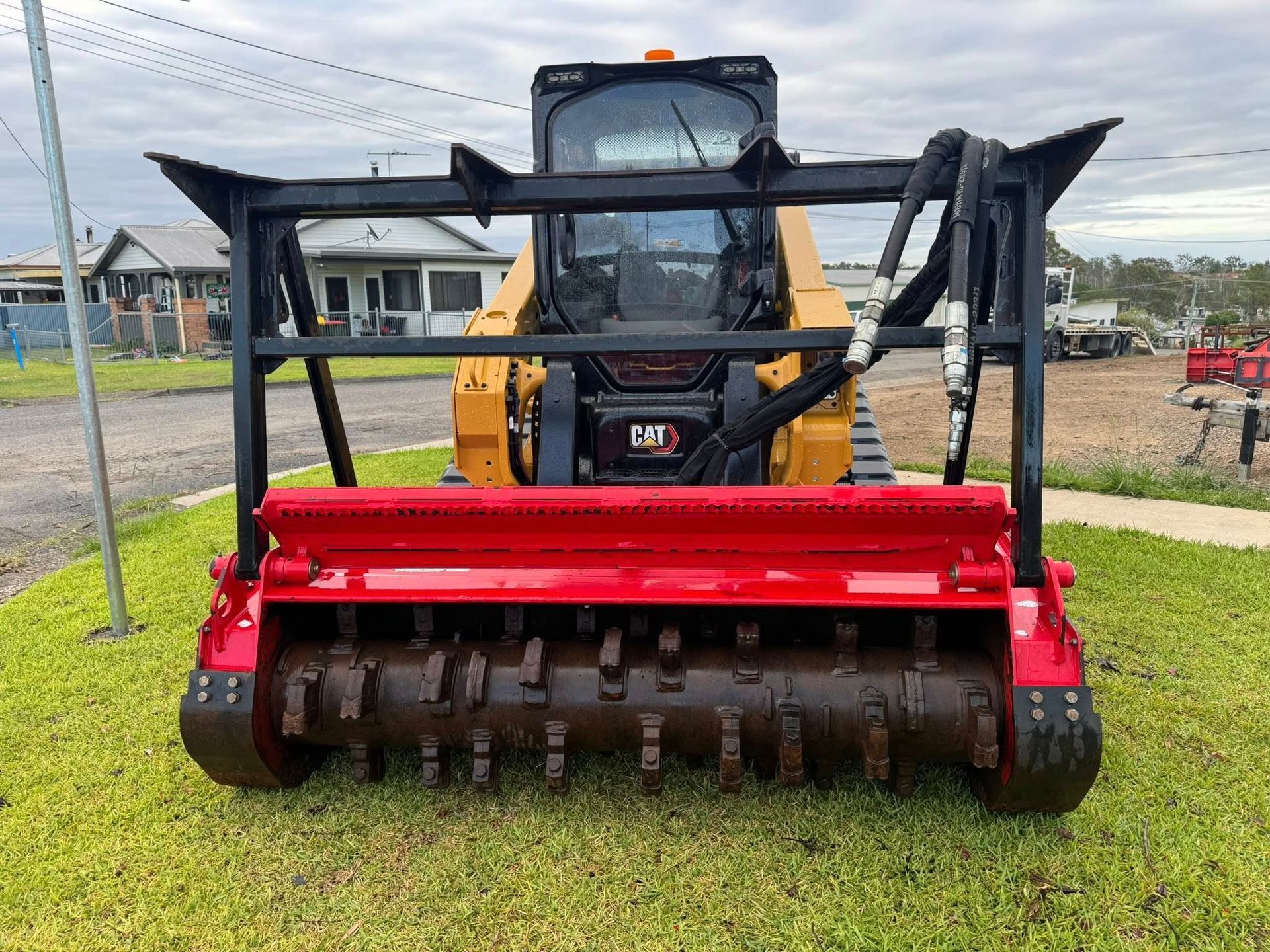 Yellow Skid Steer With Red Brush Cutter Attachment on Grass — Ovannah Hire In West Kempsey, NSW