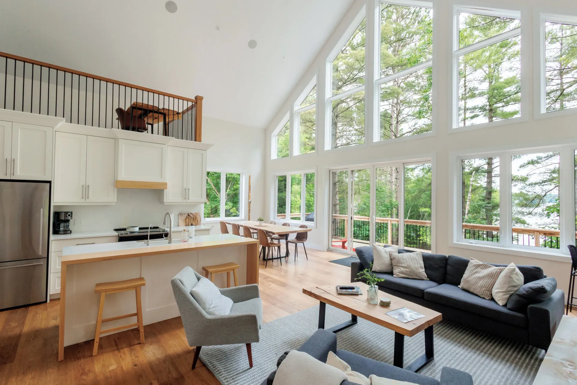 A living room and kitchen in a house with a lot of windows.